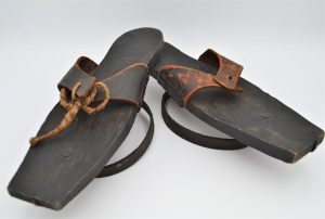 Two broad soles of sandals have metal rings attached to their bases