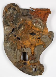 The front of cheekpiece 3 of the Hallaton helmet, which is corroded but shows details such as the ear guard