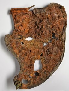 The back of cheekpiece 3 of the Hallaton helmet showing corrosion and holes where some material is missing