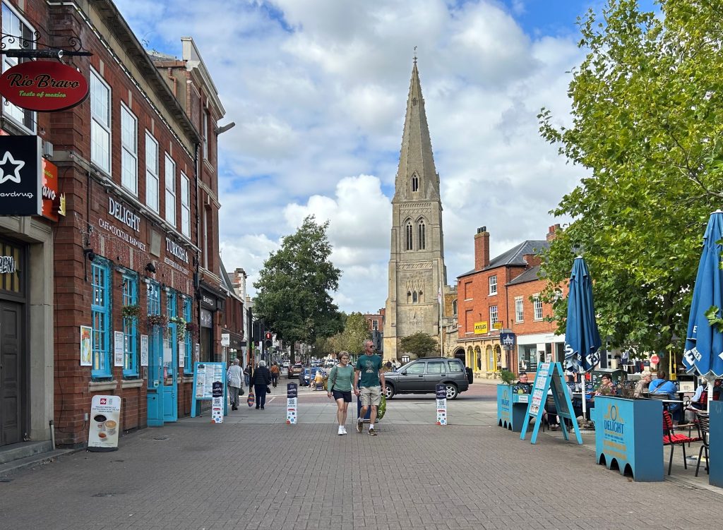 A town street with shops to one side and a church in the distance