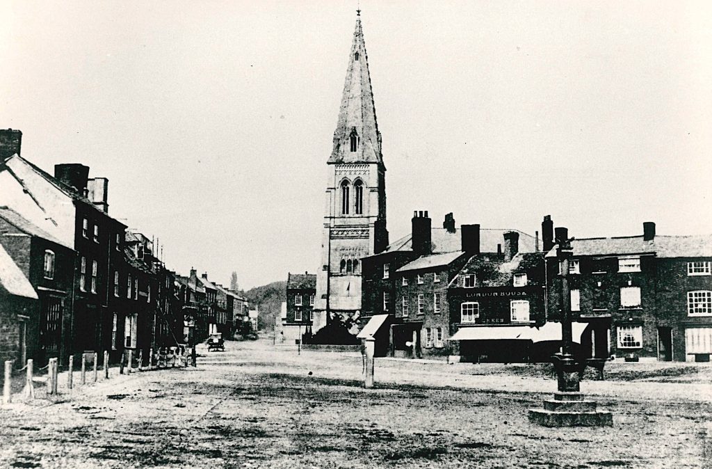 A town street with shops to each side and a church in the distance