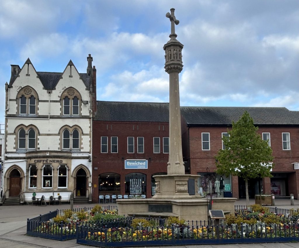 A row of cafes and shops with a war memorial in the foreground
